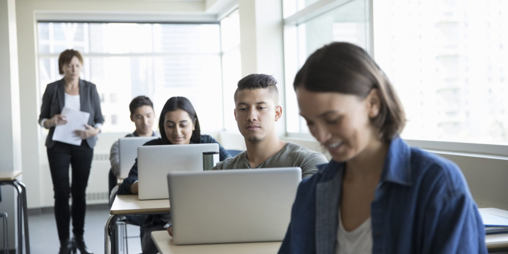 College students using laptops at desks in classroom