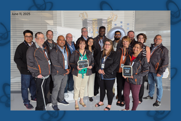 A group photo showcasing some of the MERLIN team in front of a decorative backdrop. 